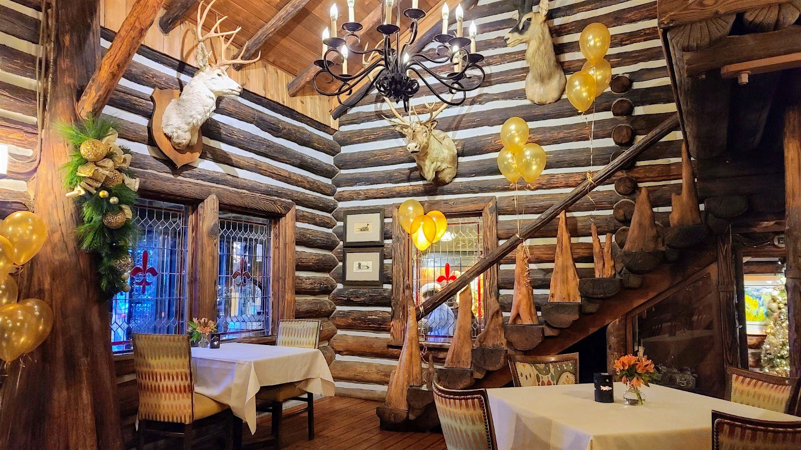 The dining room at Rainbow Lodge, lined with logs, with stained glass windows and trophies of deer on the walls